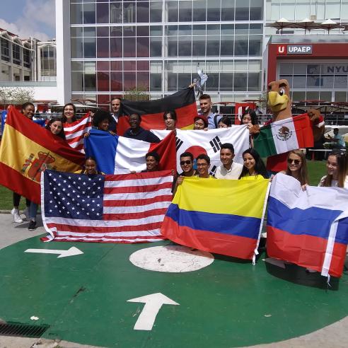 A group of students study aboard in Puebla taking a group picture while displaying the flags of various countries,