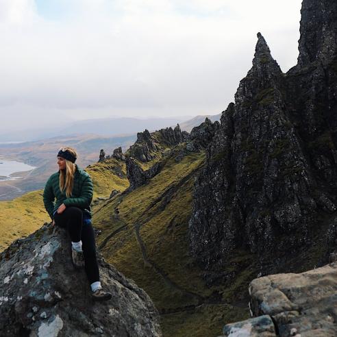 A student on a study abroad program in Scotland, Stirling taking a picture on a rocky peak with beautiful scenario background