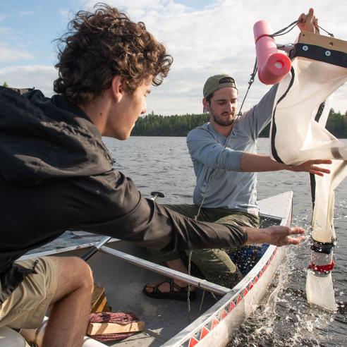 Two students in a canoe conducting an experiment on a lake for sustainability