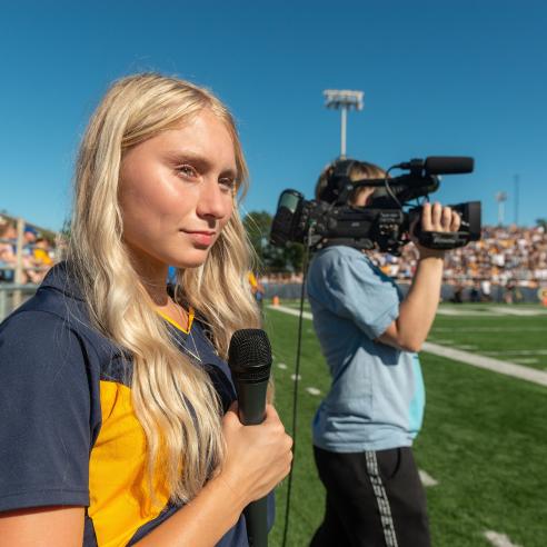 A picture of student reporter and camera man at the sport game field