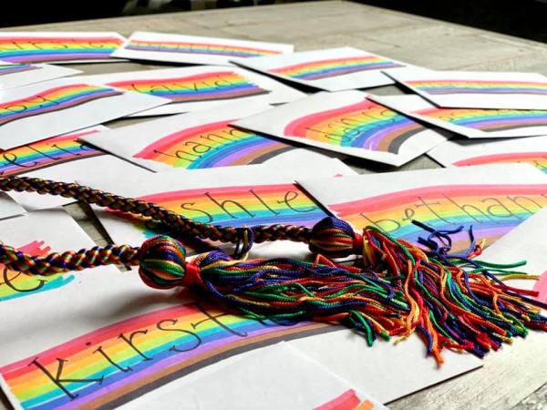 Rainbow graduation cords lay atop name placards.