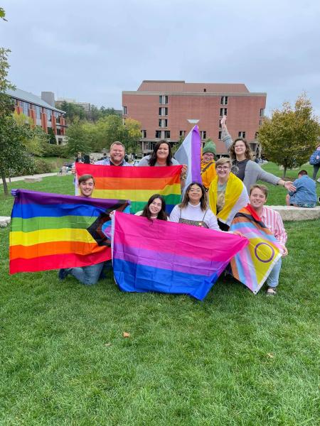 A group of people pose with colorful flags.