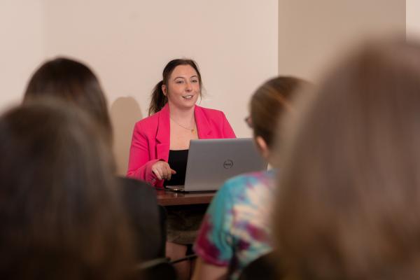 Student presents research to group from behind laptop.