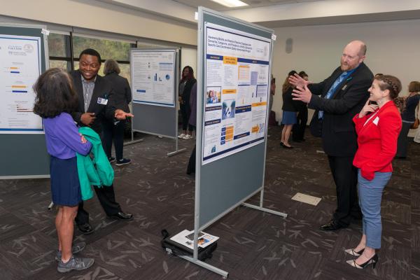 Students share research posters with event attendees.