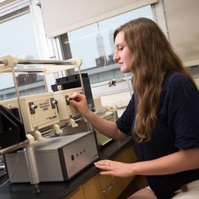 Chemistry student turns a dial on a piece of chemistry equipment