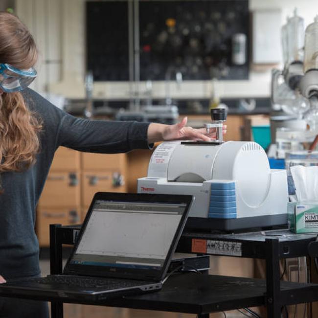 Student uses a piece of chemistry equipment wearing lab goggles