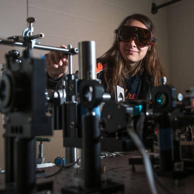 Student wearing protective goggles uses chemistry equipment in a lab