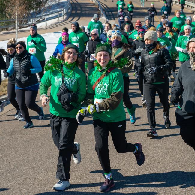 A group participants in a Shamrock Shuffle fundraiser dressed in festive green shirts and accessories showcasing community spirit