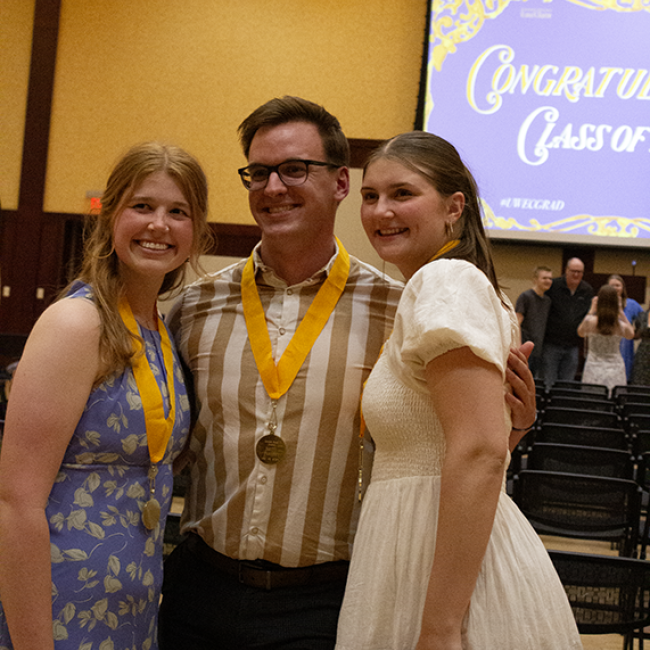 three students smile at graduation