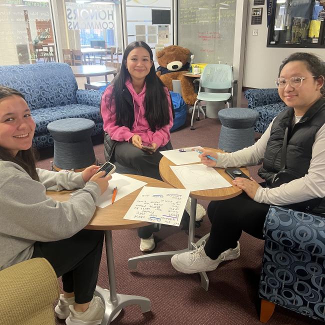 three female students sit around a table