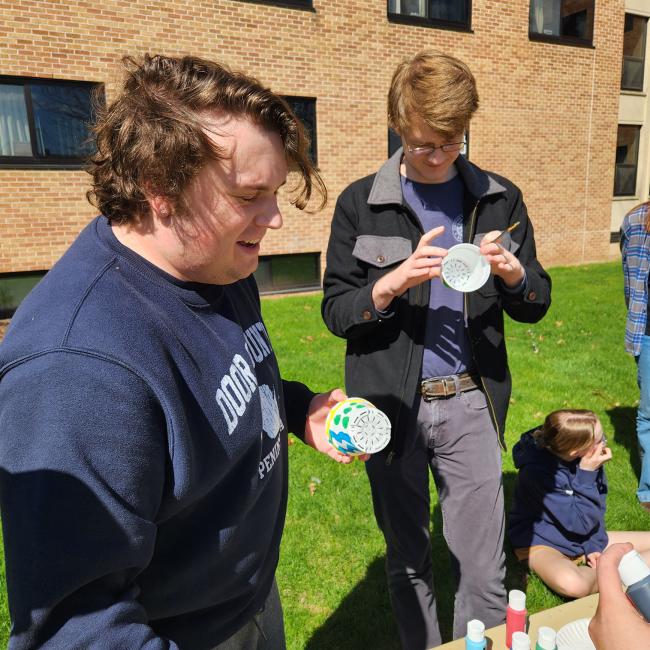 two students outside painting pots