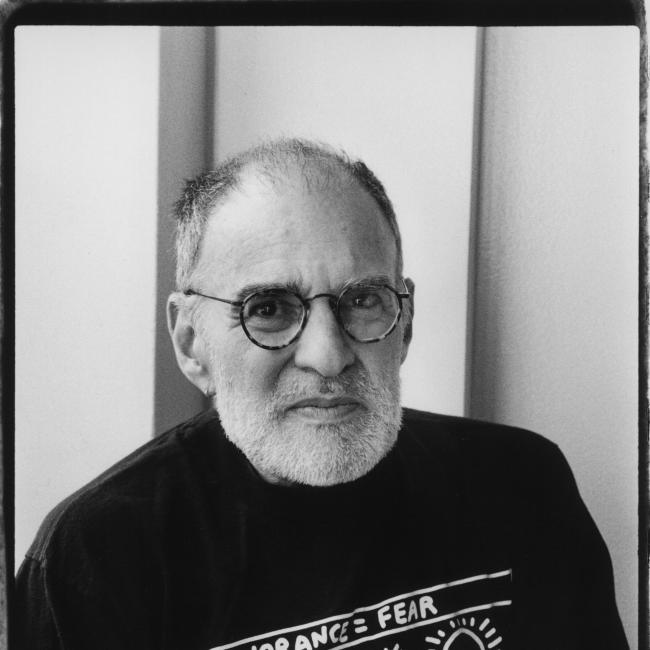 A seated man smiles for the camera. 