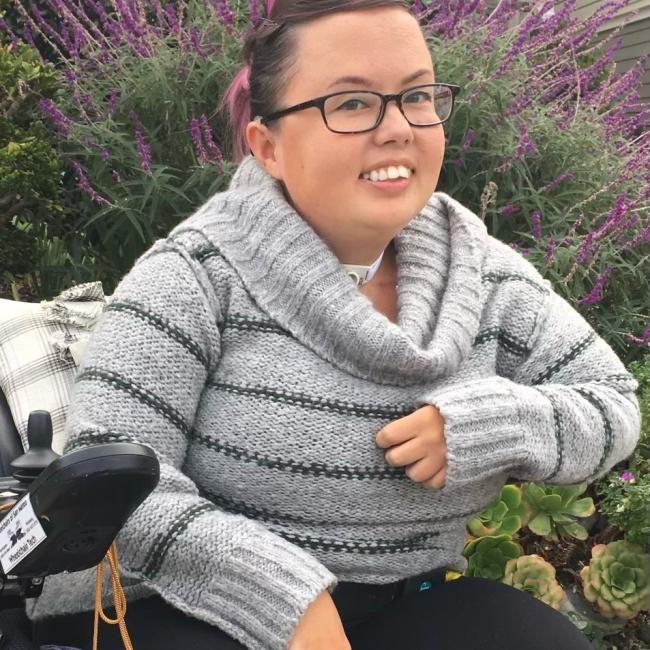 A woman in a wheelchair smiles for the camera. 