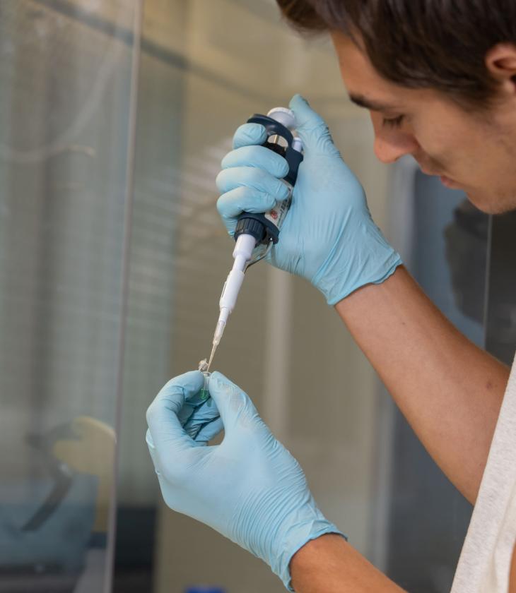 biomed lab male research student filling vials 