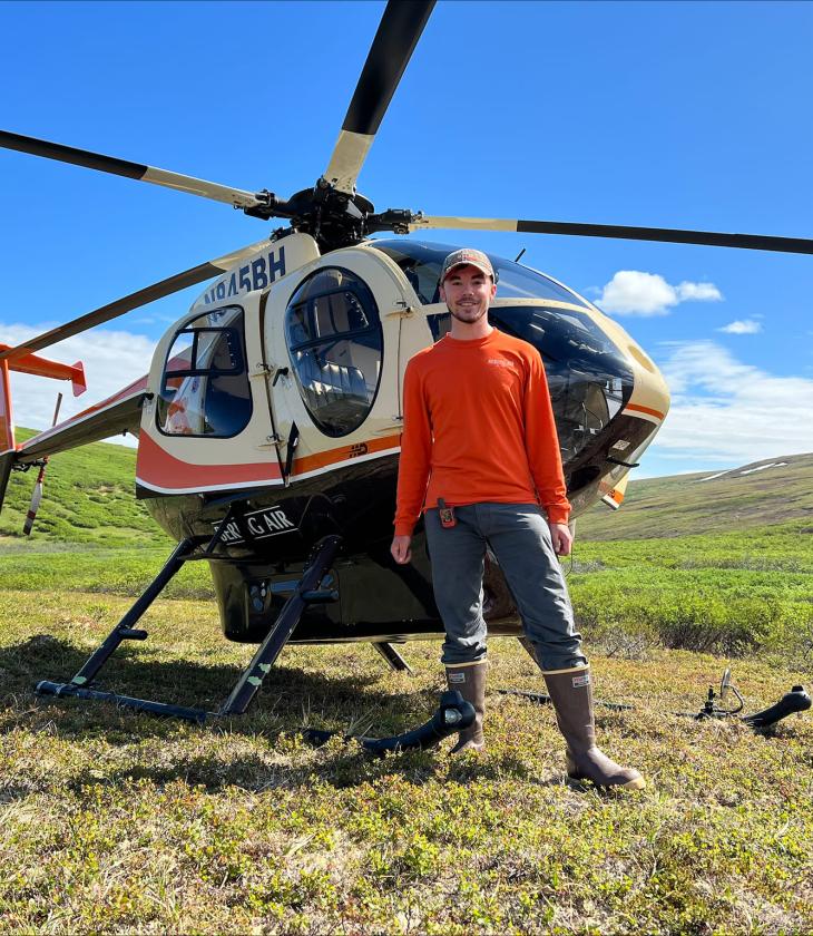 geology intern standing by a helicopter in Alaska