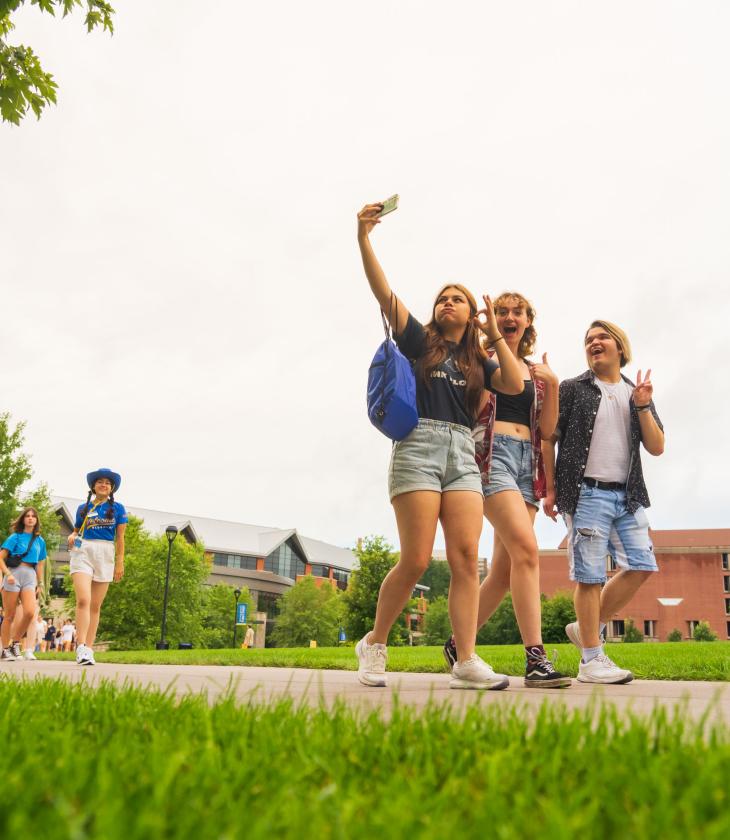 three visiting students taking a selfie on the mall sidewalk 