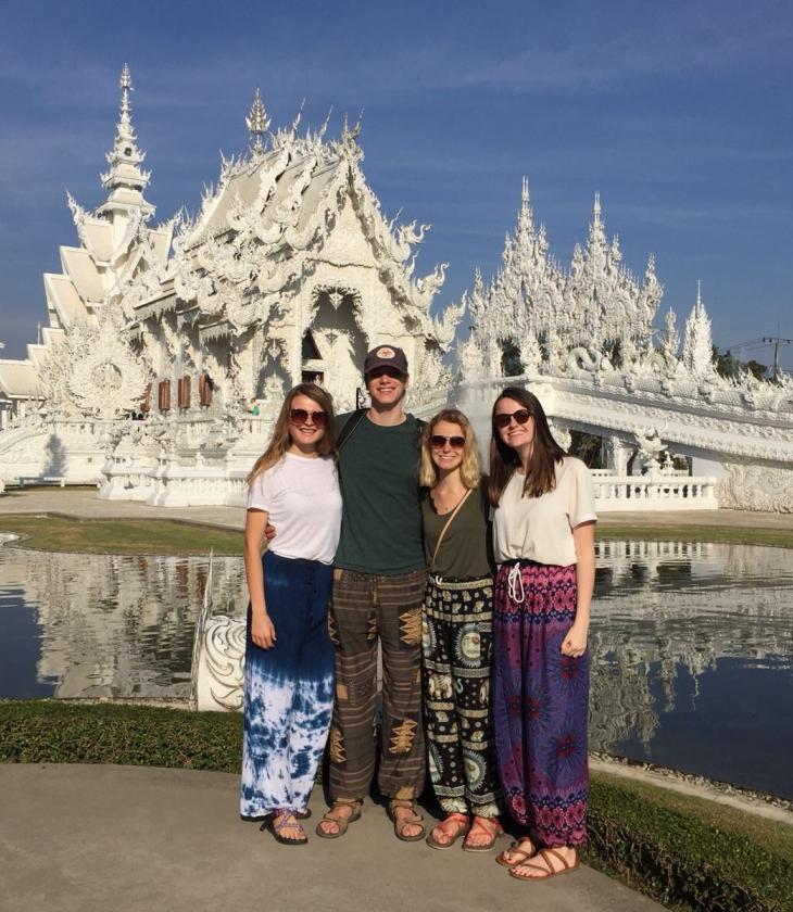 A group photo of students on a study aboard trip to Thailand posting in front of the white temple