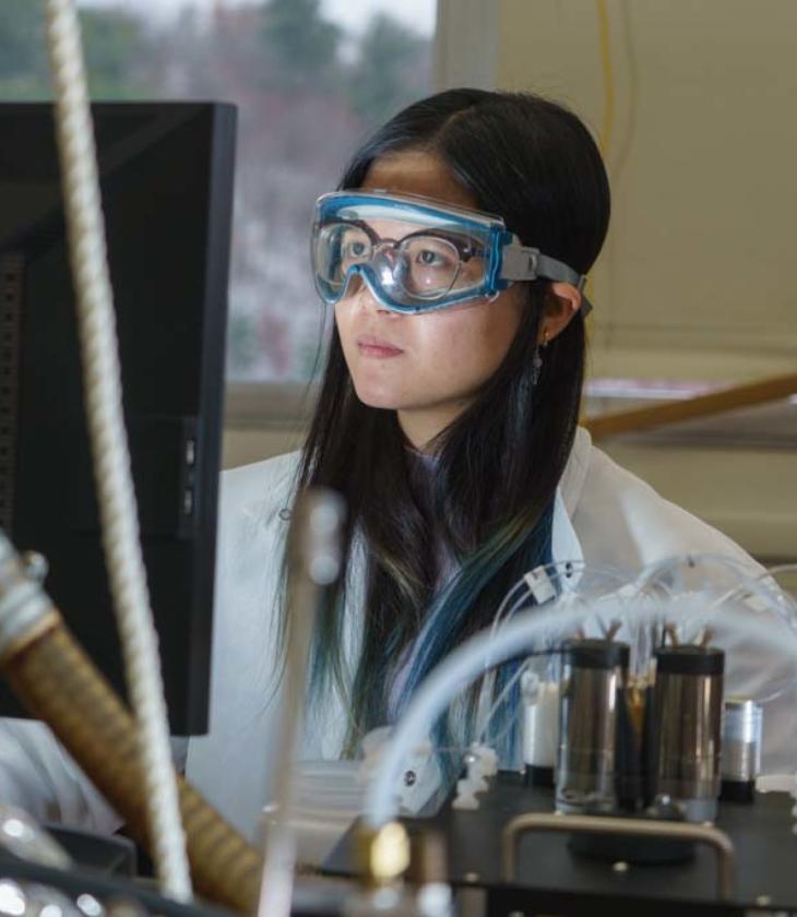 student in lab wearing goggles and viewing a monitor 