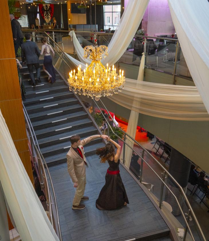 Viennese Ball, students twirling under chandelier on grand staircase 