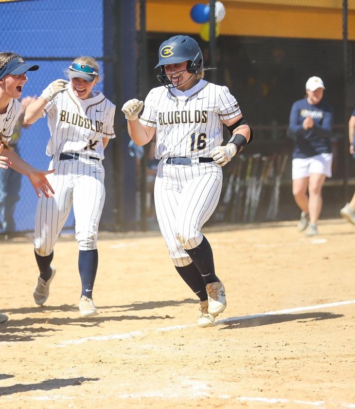 Softball players celebrate at home plate. 