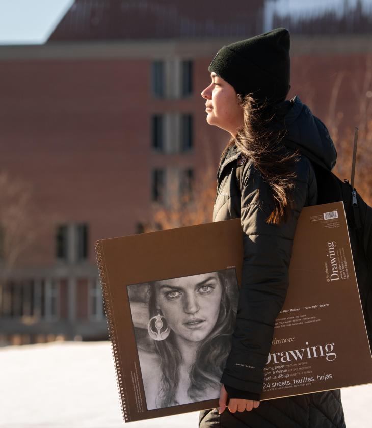 Student walking to class with drawing book