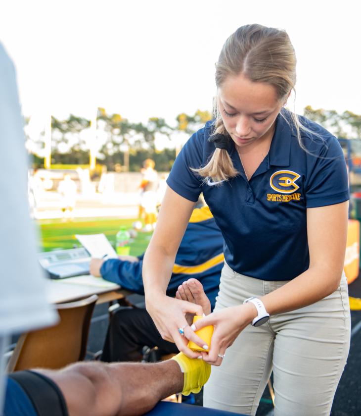 Student taping an ankle during a UWEC soccer game