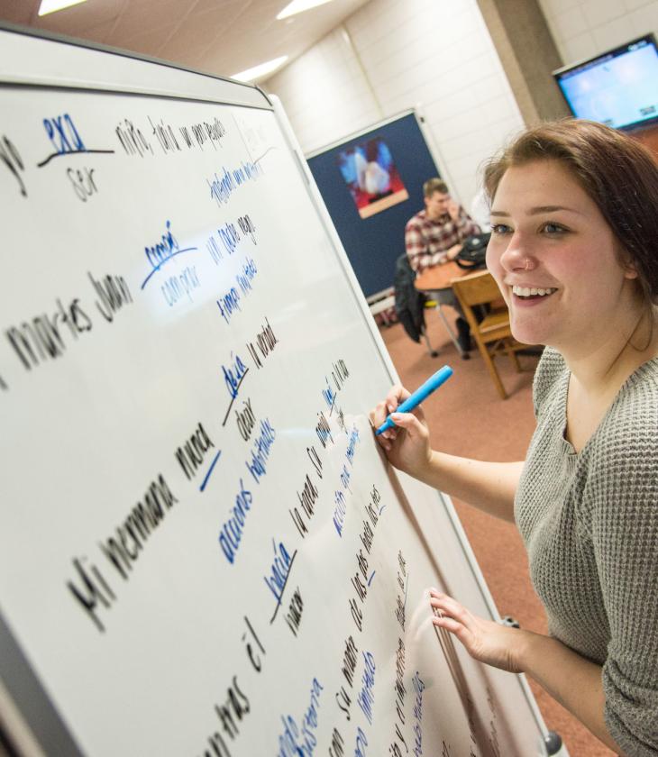 Student studying Spanish on a white board