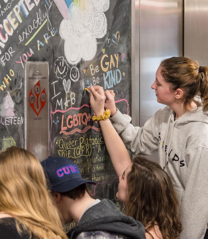 Students drawing on the chalkboard on the Rainbow Floor