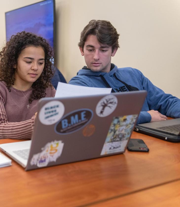 Students look at laptops during a business class.