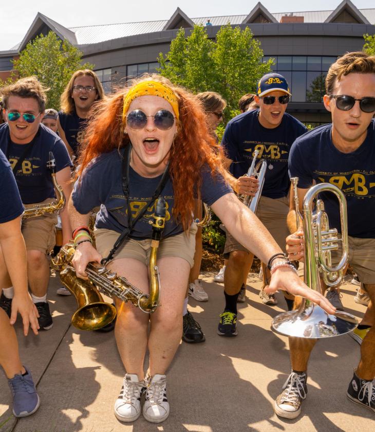 Members of the marching band cheer and pose for a photo with their instruments and matching t-shirts