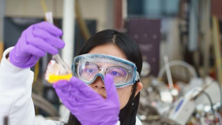 student holding beaker of orange liquid in chem lab