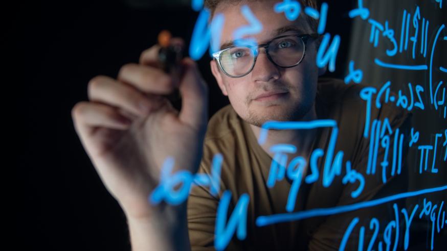 Tyler Gonzales writing math on a light board