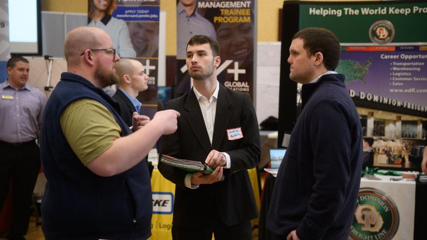 Male marketing students talking with business at career fair