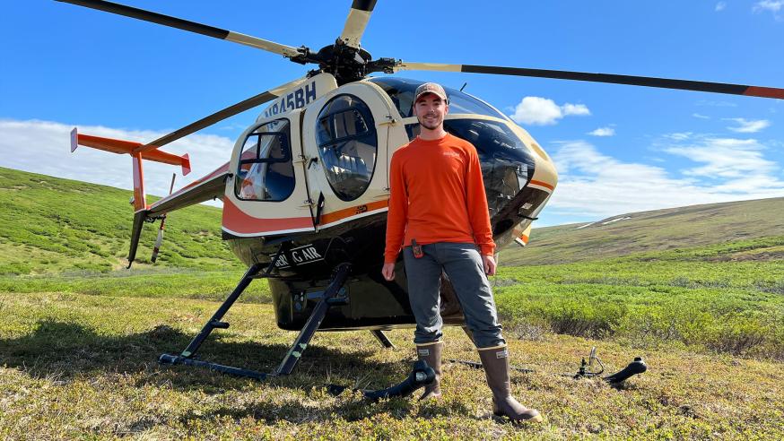 geology intern standing by a helicopter in Alaska