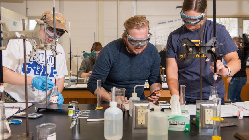 Students in a chemistry lab complete an experiment wearing safety goggles.