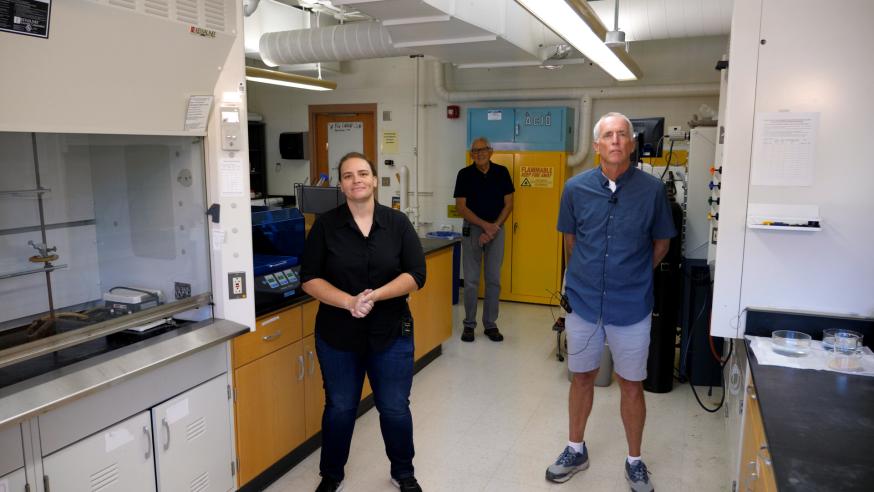 three faculty, two men nd one woman, in a chemistry lab