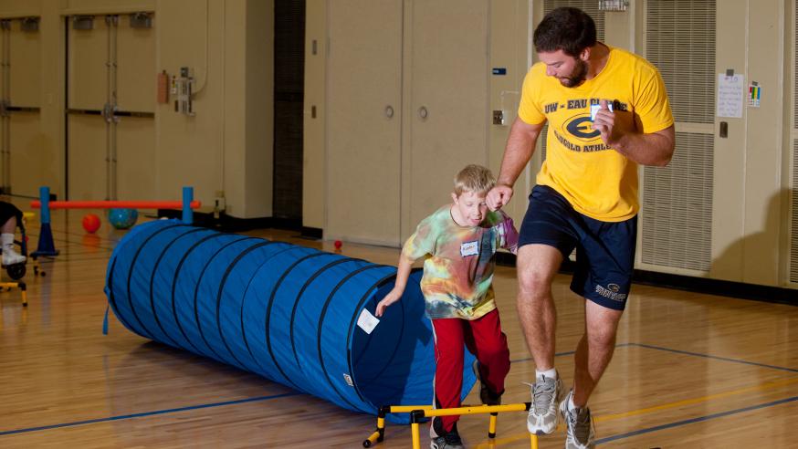 students helping youger students Student teacher helping boy get active.