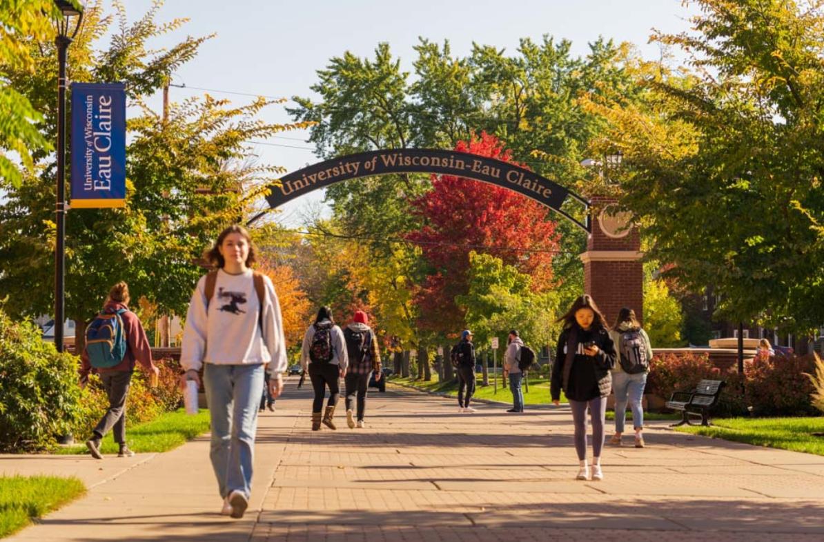 Students walking along UWEC pathway in autumn foliage 