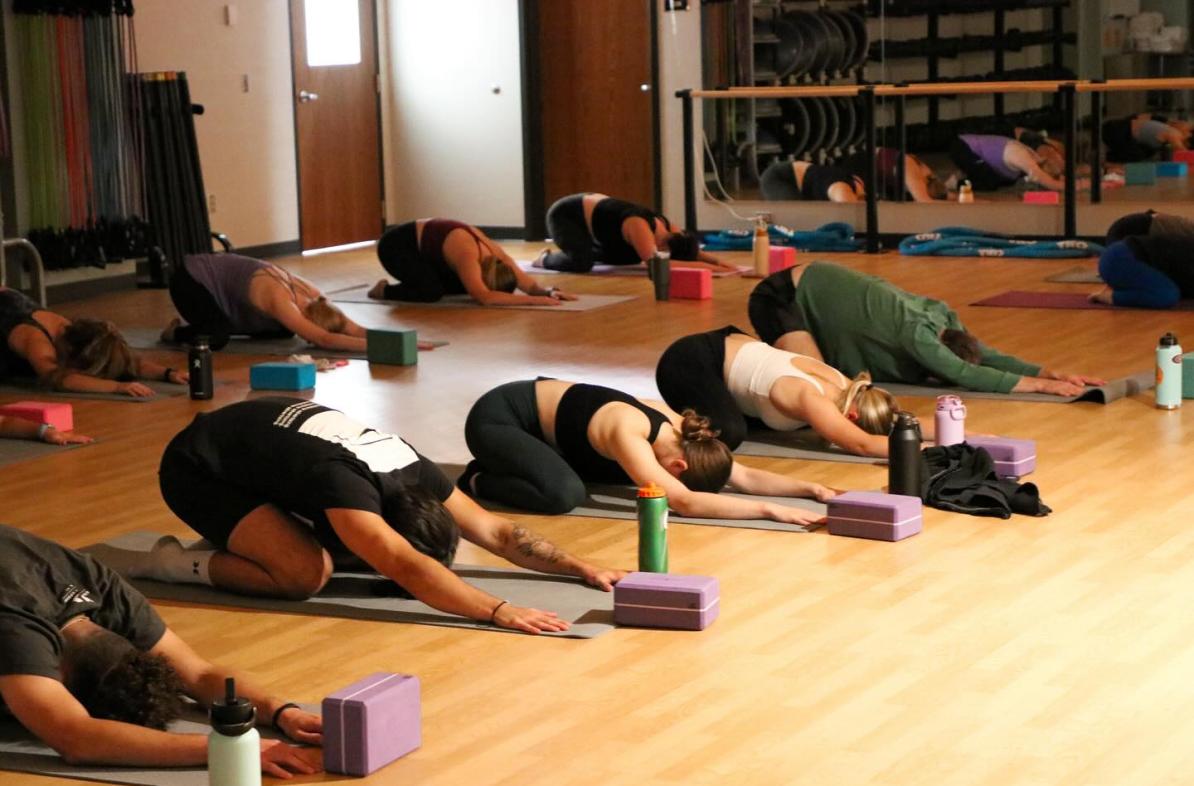 yoga class, indoors, all participant in child's pose face down 