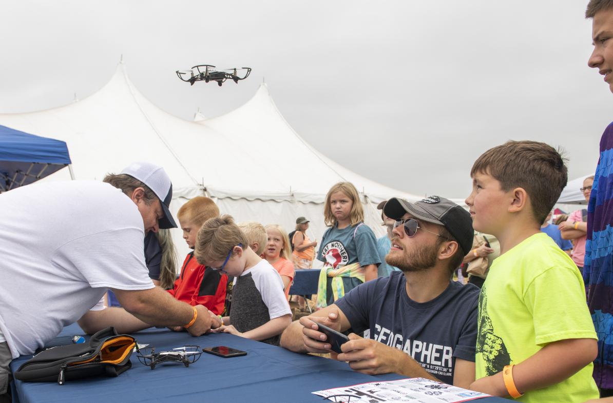 Kids and college student at toy drone table event