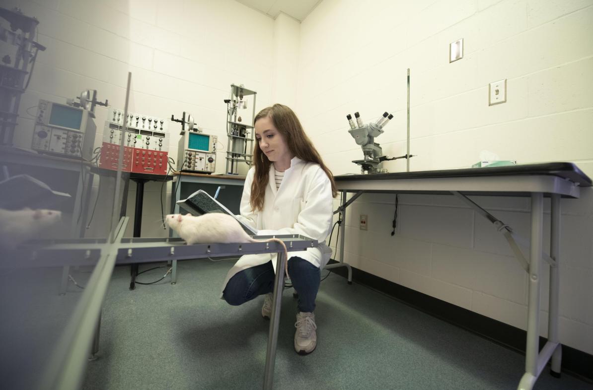 female student in neuroscience lab with white rat