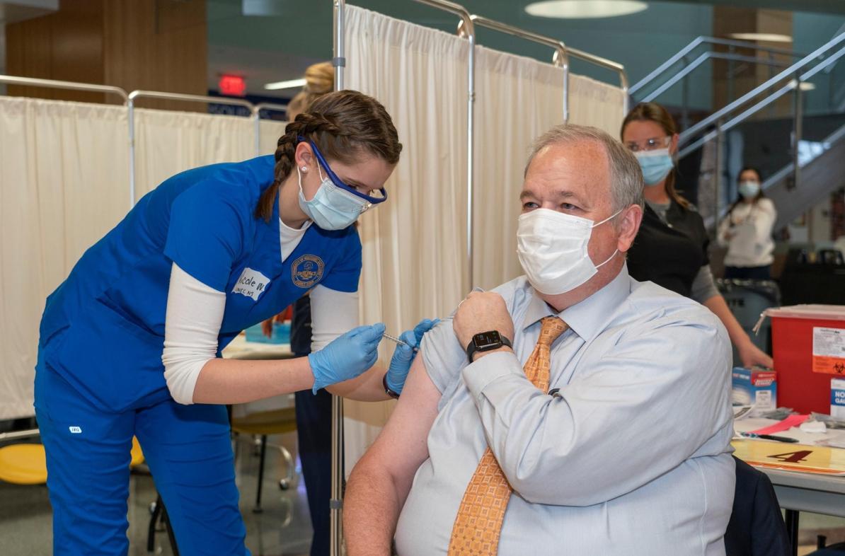 Chancellor Schmidt receiving a vaccination from a nursing student