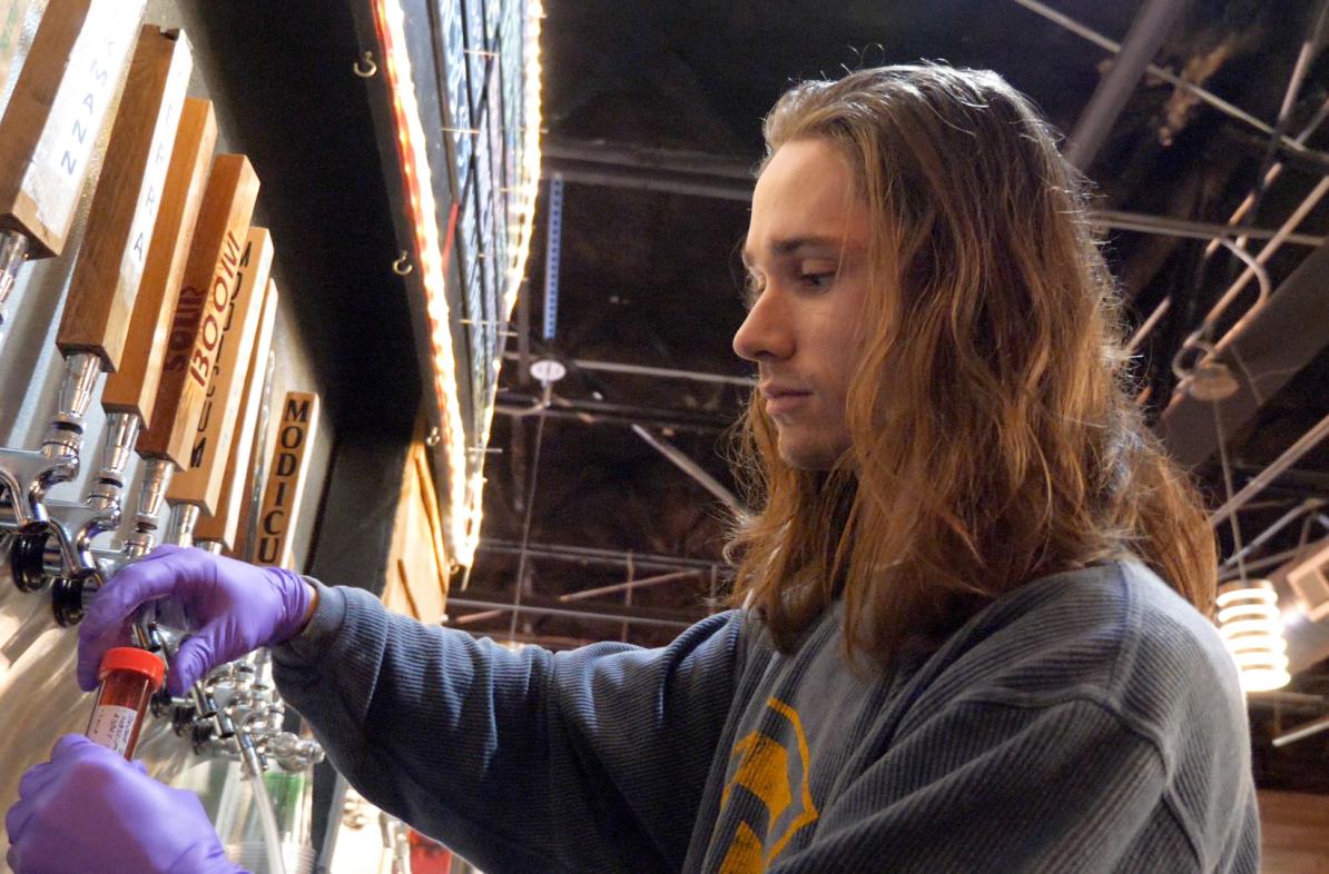 male student tapping beer in a local brewery