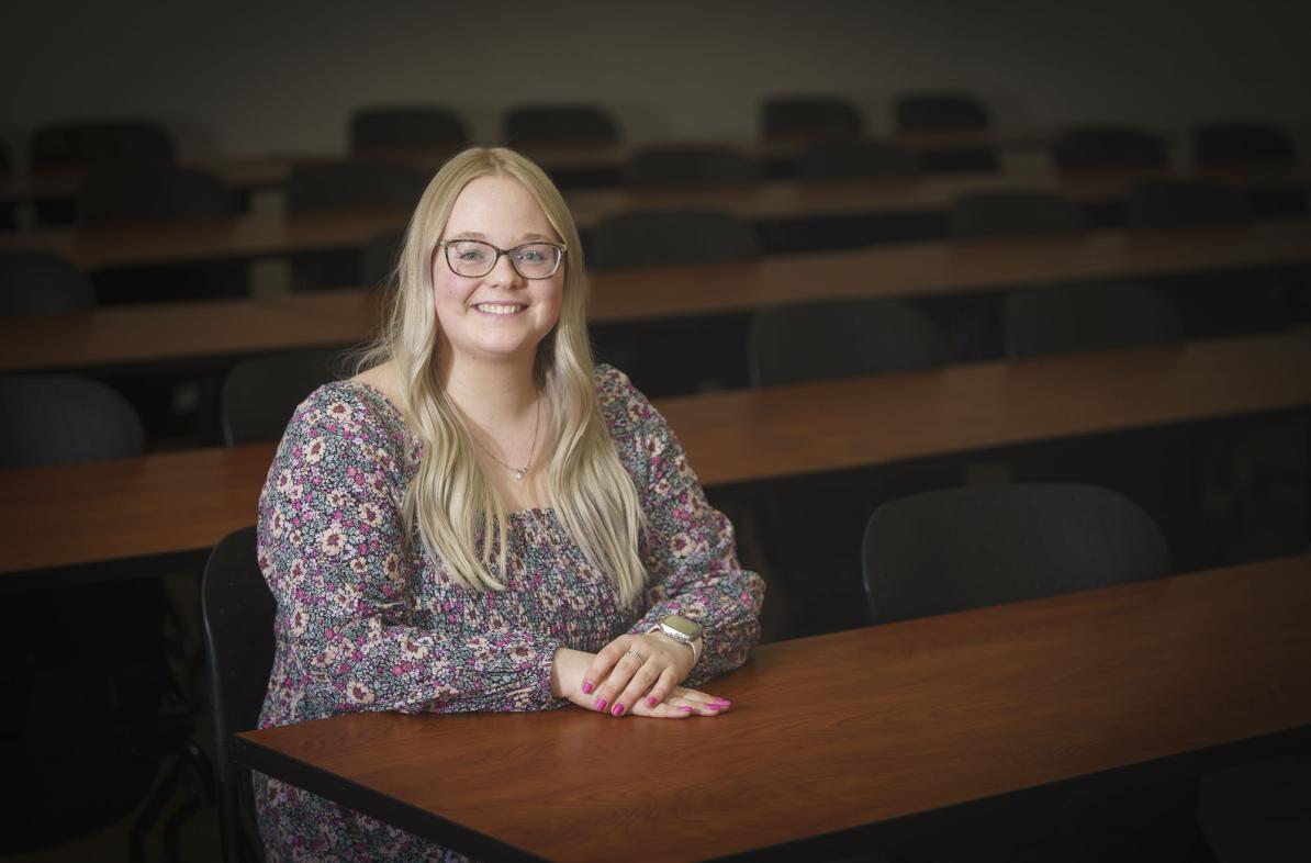 Grace Olson, female NCUR research student sitting at a desk, long blond hair, smiling.