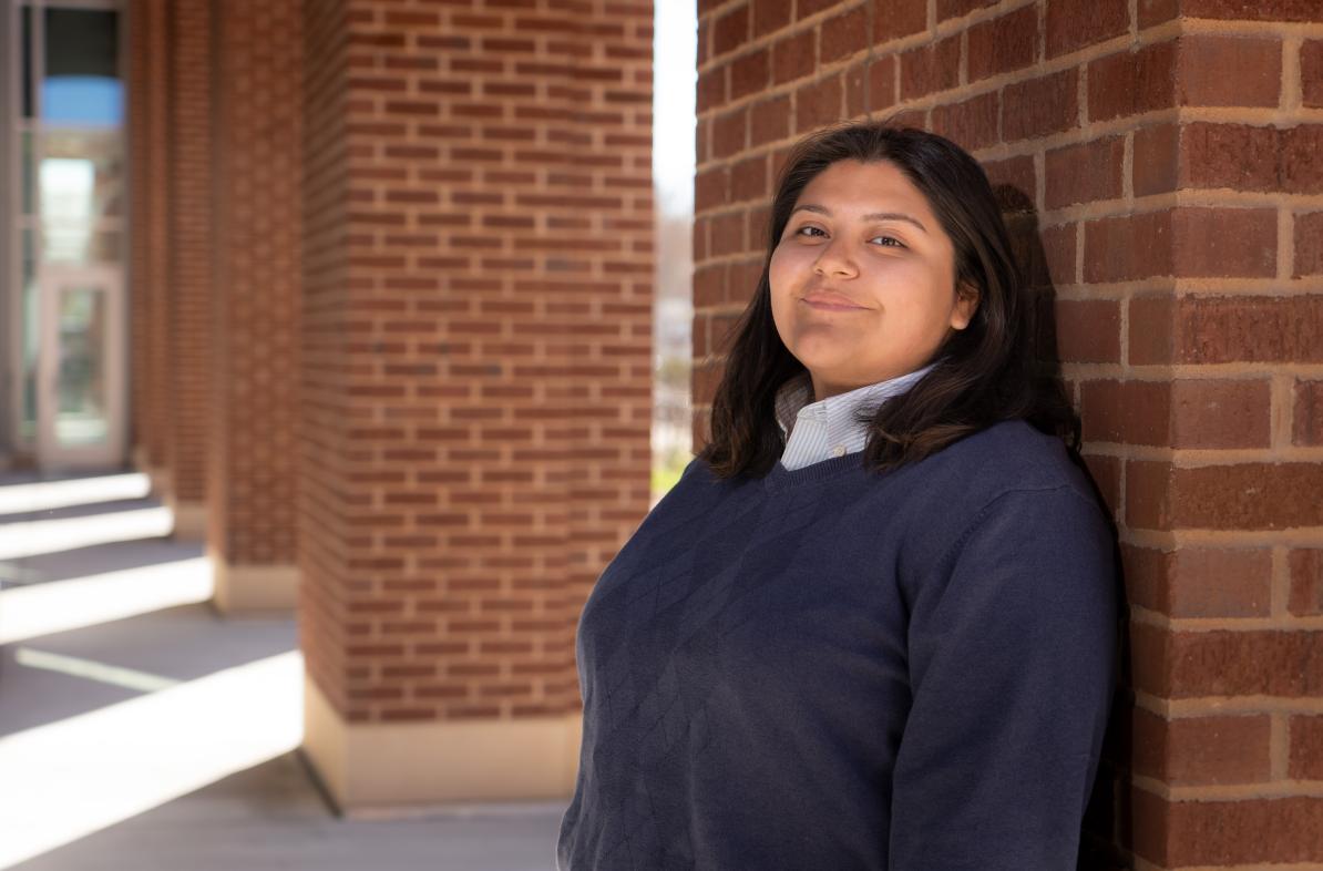 female student outside Centennial Hall leaning on brick column