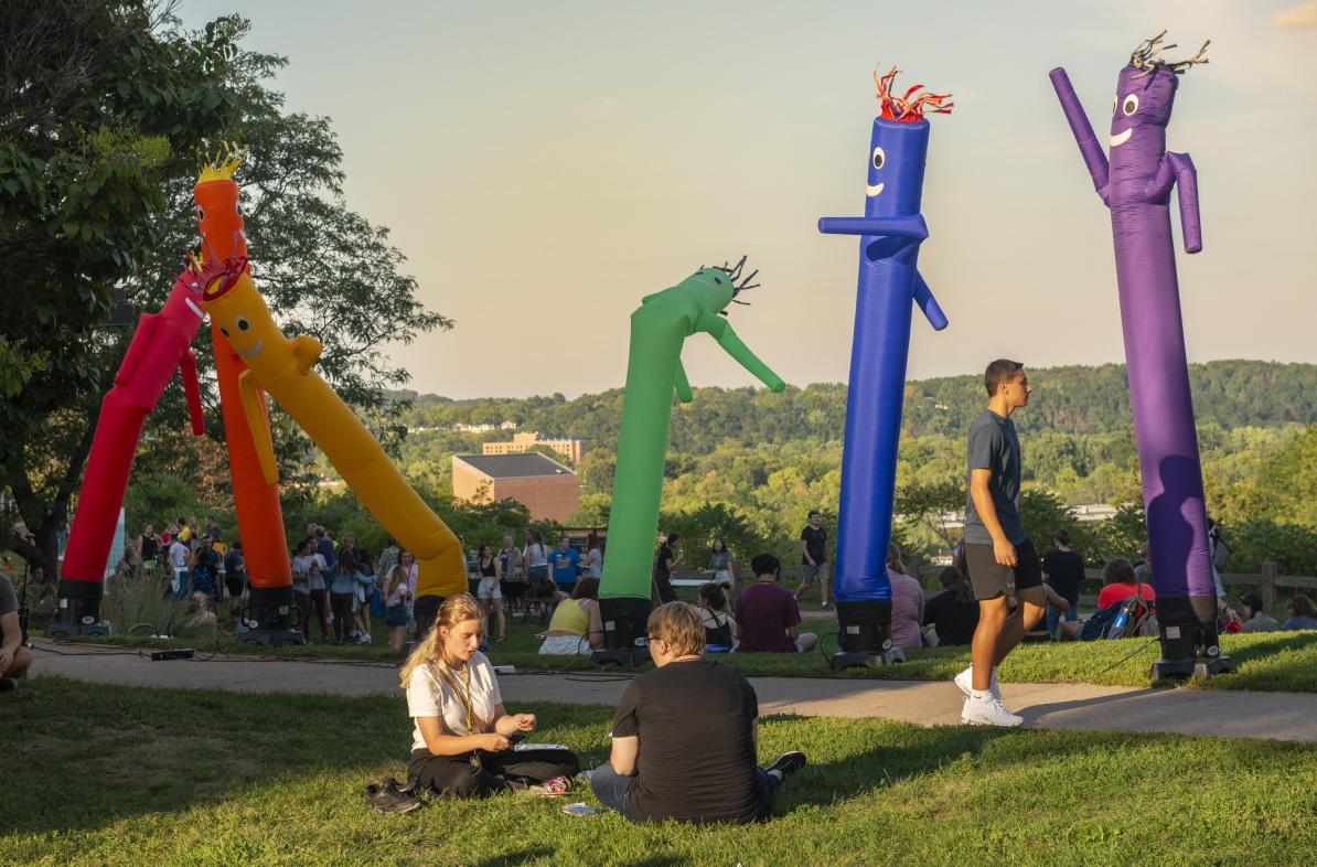 Rainbow inflatable people and students walking past