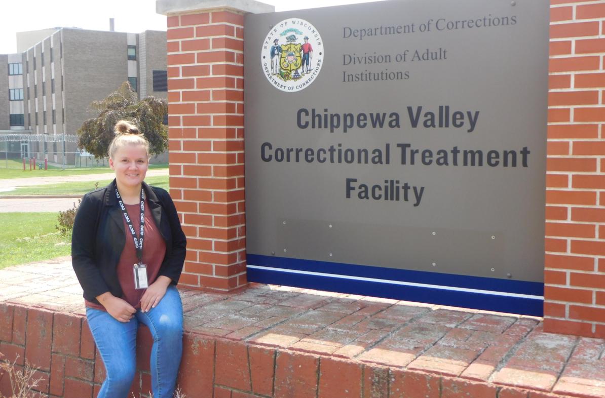 female student seated in front of signage at the Chippewa Valley Correctional Treatment Facility