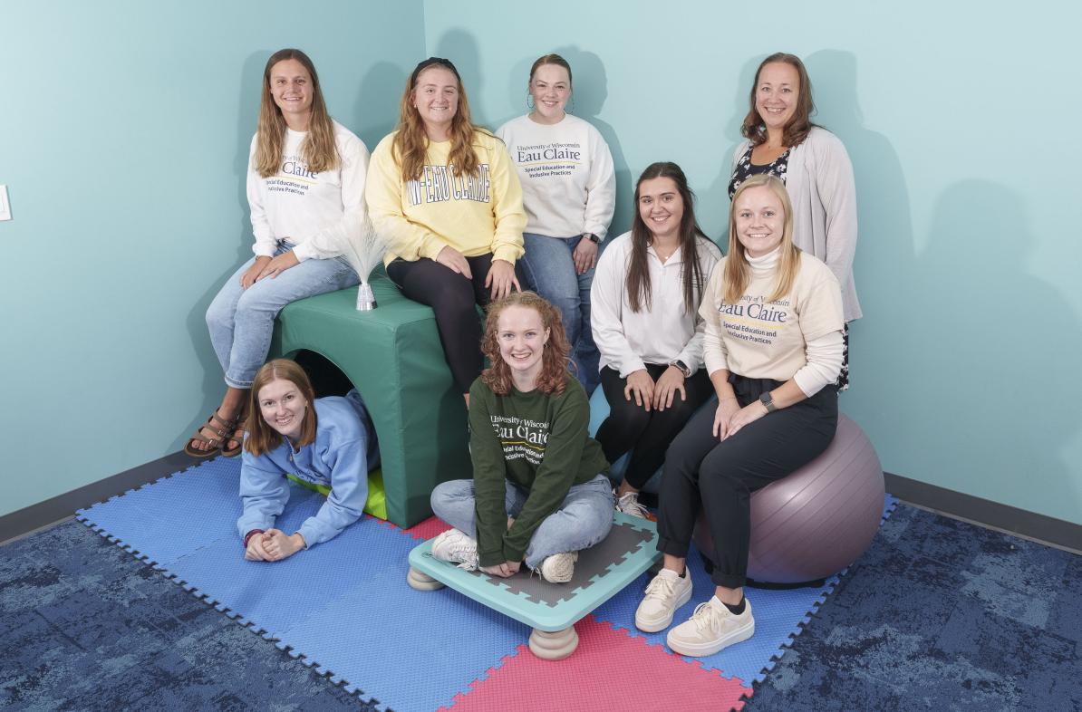 The research group of students and their professor pose in the sensory room they helped design.