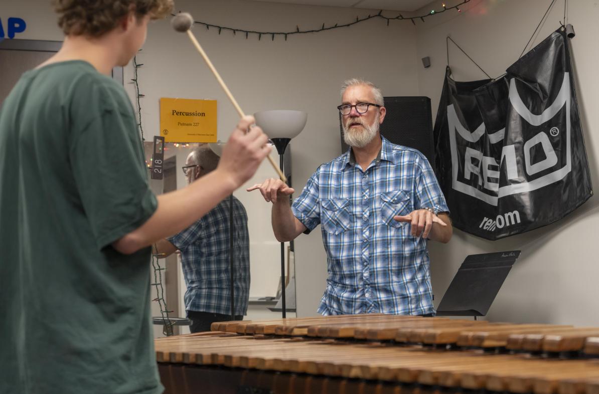 Jeffrey Crowell, music profesor, in a small group percussion lesson in Haas Fine Arts with two students, one make and one female.