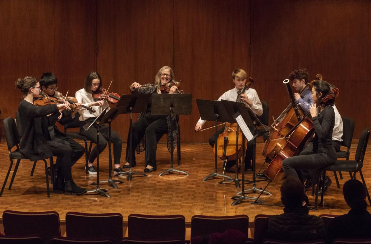 students in a small ensemble playing strings with an instructor